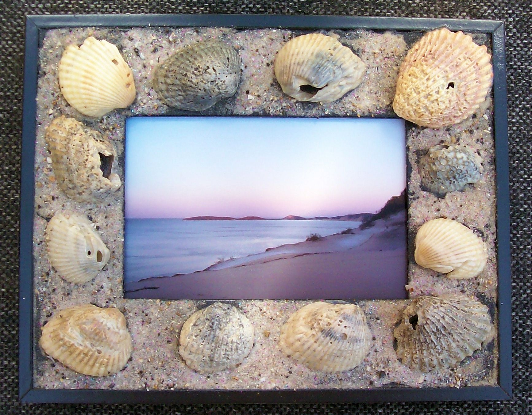 Broken shells and sand glued to picture frame.